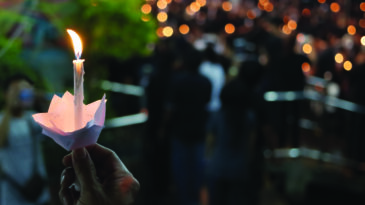 Hand of man hold candle flame light at night with bokeh background