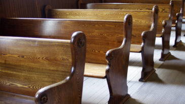 Carved Wooden pews in church in sunshine