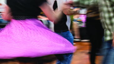 People enjoying dancing at a dance club. Motion blur of pink flying skirt captured in camera by using slow shutter speed.