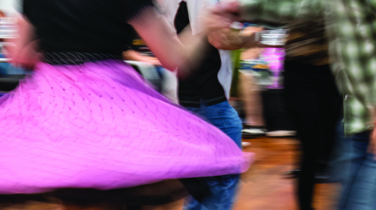 People enjoying dancing at a dance club. Motion blur of pink flying skirt captured in camera by using slow shutter speed.