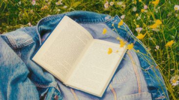 White book on blue jean jacket in field of wildflowers. Warm sunshine.